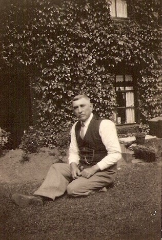 Bill in the garden at 54 Delph Road. The house is covered in ivy,